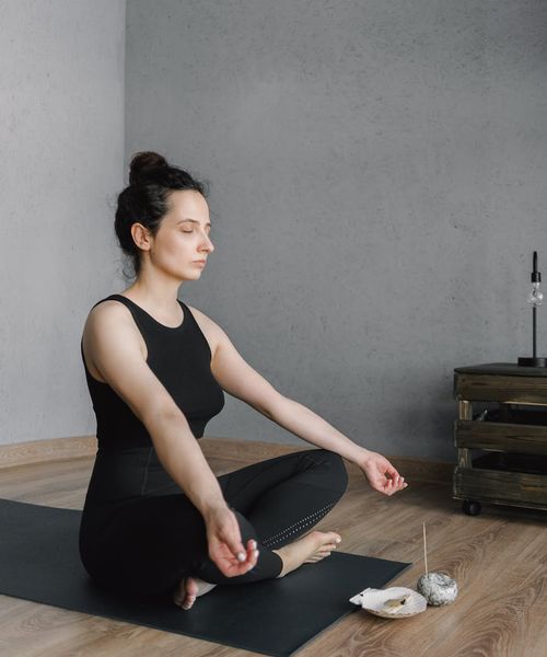 Person meditating peacefully in a bright, modern living room.