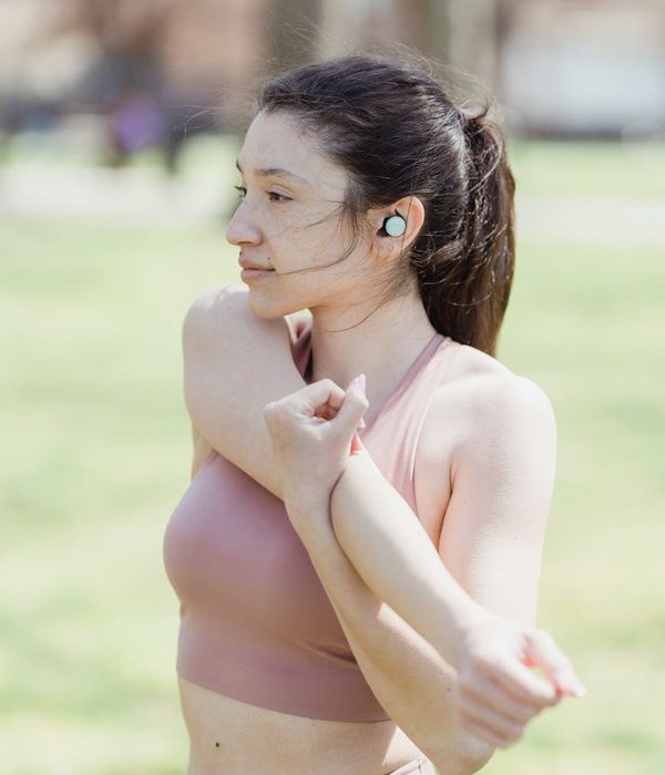 Woman feeling energetic and stretching outdoors in a park.